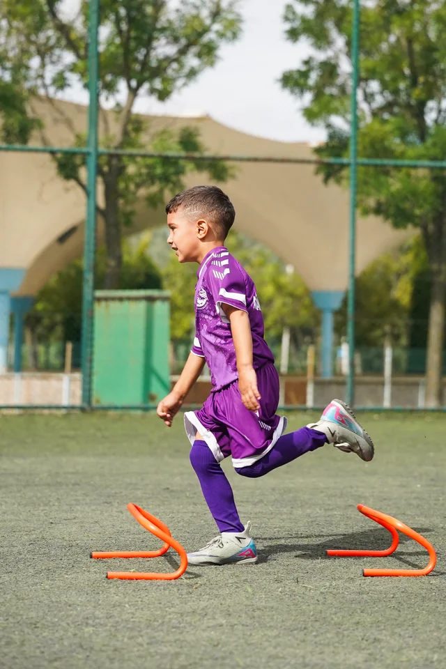 Futbol antrenmanında engeller arasında koşan genç sporcu