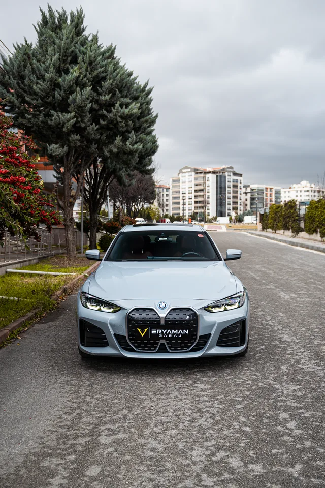 Ağaçlıklı cadde üzerinde beyaz BMW’nin önden görünümü